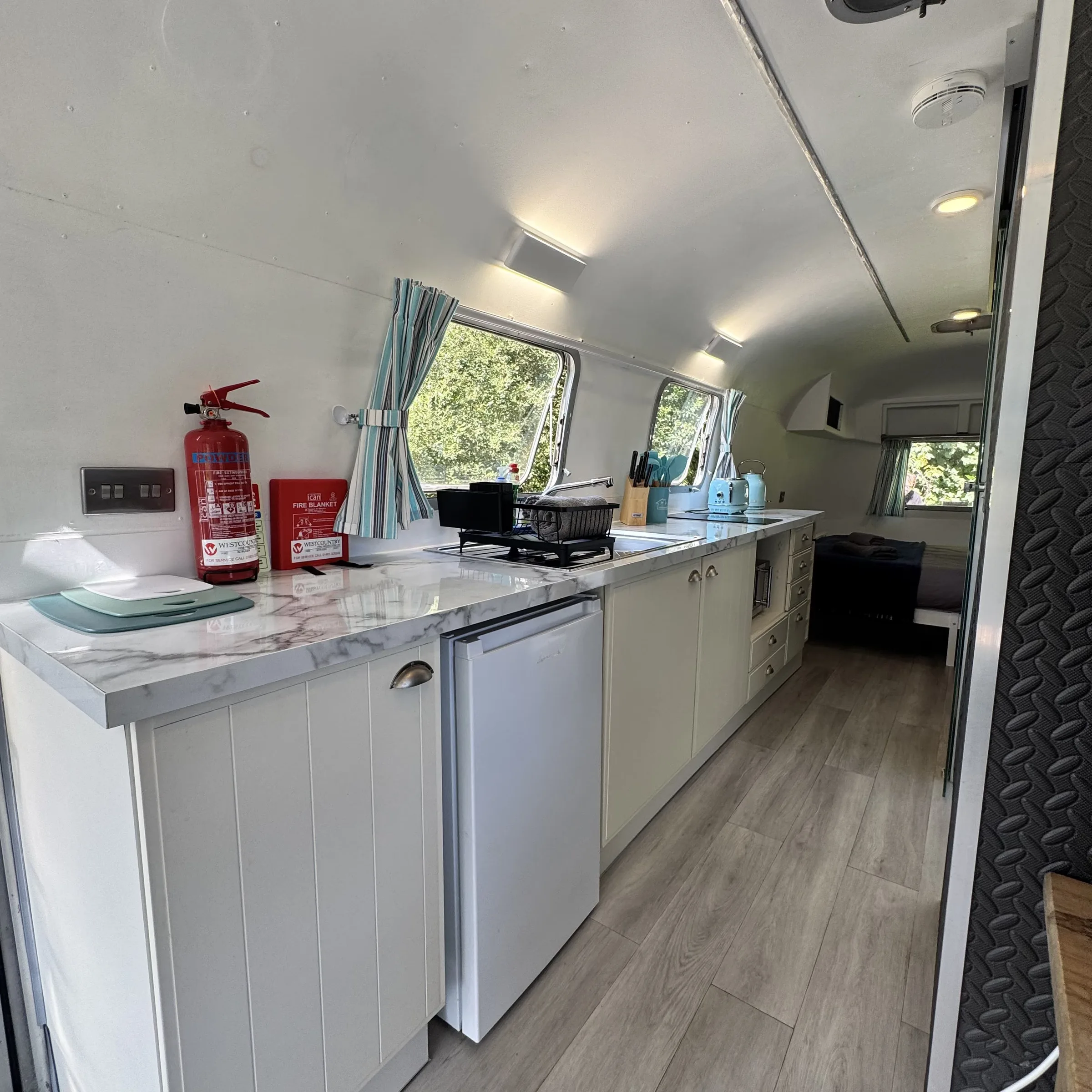 Inside the Boskenna Airstream, looking down the galley kitchen to the bed at the far end