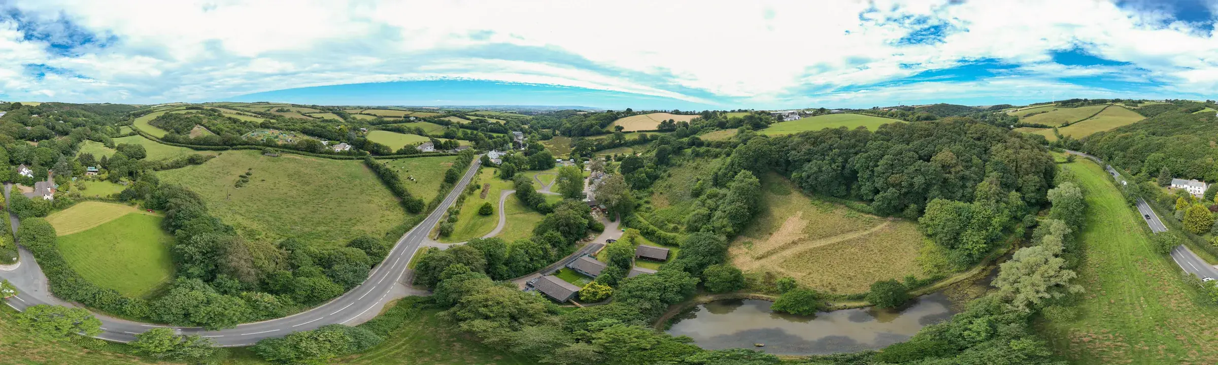 An aerial panorama of the valley, with the stream and the line of willows running through the middle of the fields